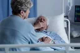 Elderly man lying in a hospital bed and coughing