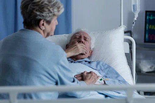 Elderly man lying in a hospital bed and coughing