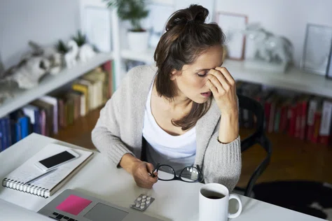 Woman at desk holding her head