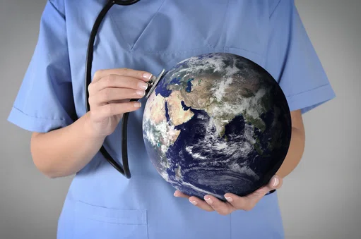 Woman holding a world globe with a  stethescope measuring health